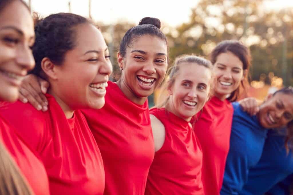 Womens Football Team Hugging After Training For Soccer Match On Outdoor Astro Turf Pitch